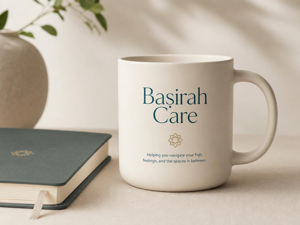 A minimal cream ceramic Baṣirah Care mug beside a notebook in soft studio light
